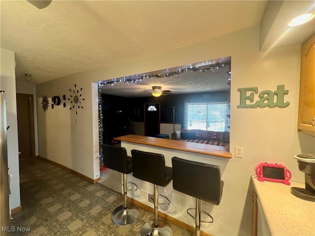 kitchen featuring dark floors, light countertops, a textured ceiling, and baseboards