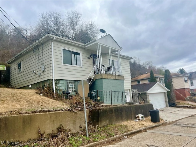 view of front of house with an outbuilding, concrete driveway, covered porch, and stairs