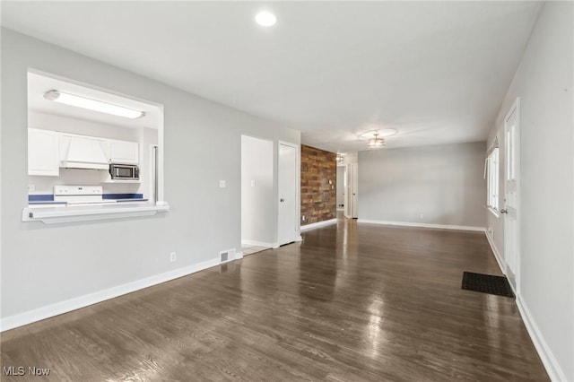 unfurnished living room featuring baseboards, visible vents, and wood finished floors