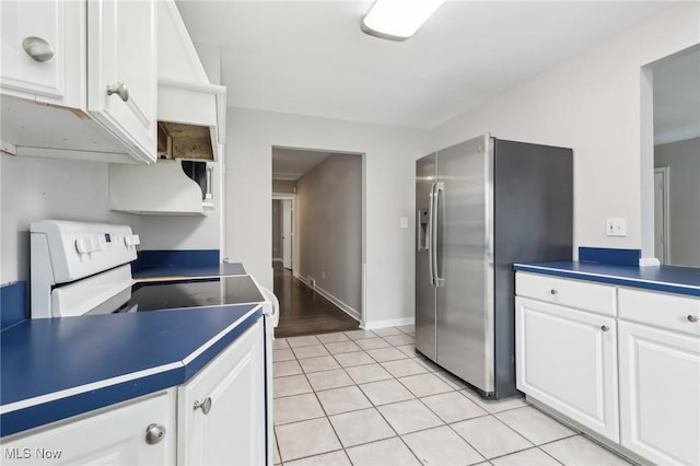 kitchen featuring white electric stove, light tile patterned floors, white cabinetry, baseboards, and stainless steel fridge