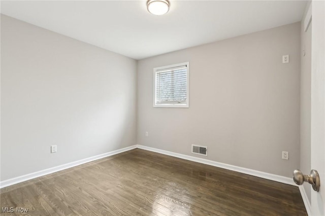 empty room with baseboards, visible vents, and wood finished floors