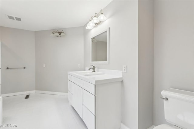 bathroom with toilet, vanity, and visible vents