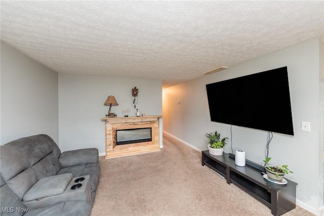 carpeted living area with a textured ceiling, a glass covered fireplace, visible vents, and baseboards