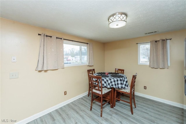 dining space with baseboards, a wealth of natural light, and wood finished floors