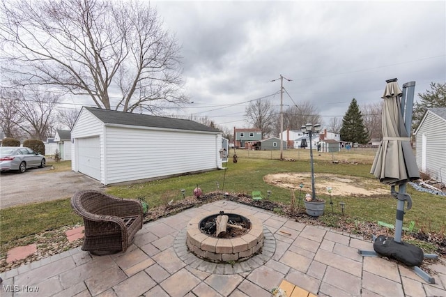 view of patio featuring a detached garage, a fire pit, and an outbuilding