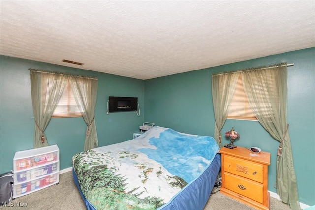 carpeted bedroom with baseboards, visible vents, and a textured ceiling