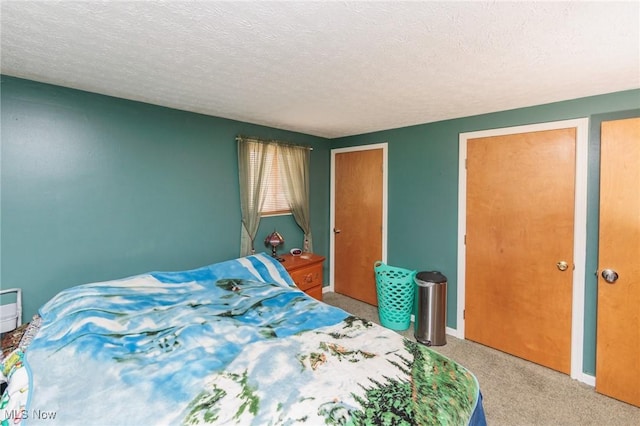 carpeted bedroom featuring a textured ceiling and baseboards