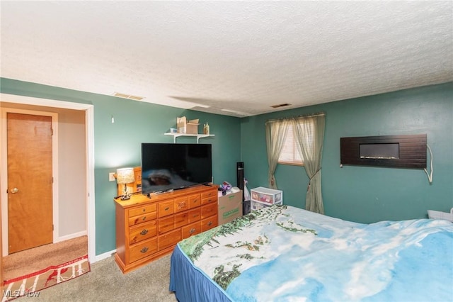 bedroom featuring carpet, visible vents, a textured ceiling, and baseboards