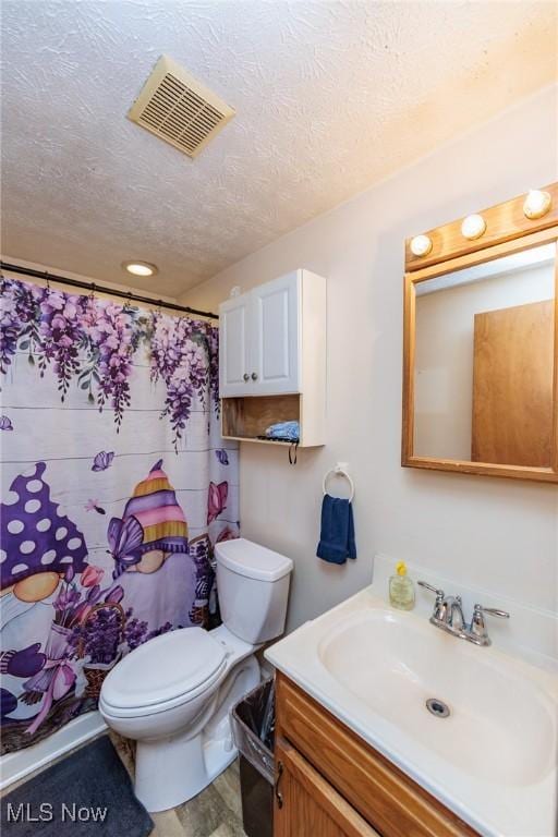 bathroom featuring a textured ceiling, toilet, a shower with shower curtain, vanity, and visible vents