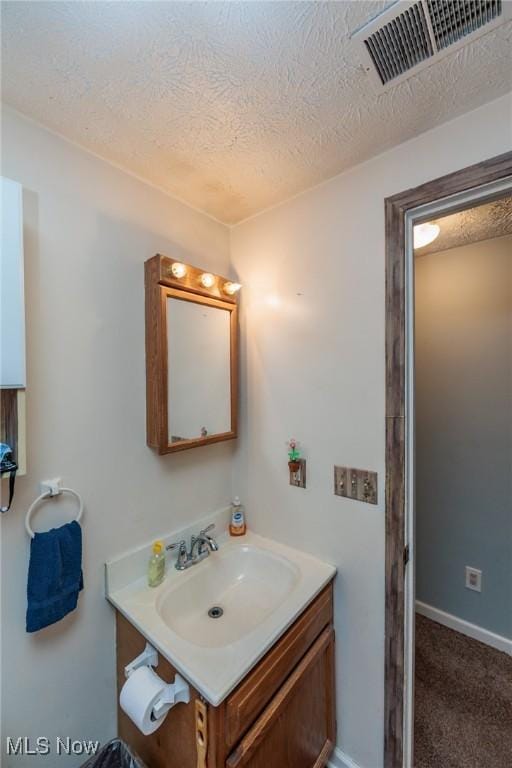 bathroom featuring visible vents, a textured ceiling, baseboards, and vanity