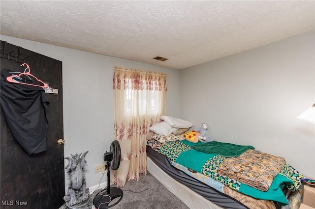 bedroom featuring a textured ceiling, carpet, visible vents, and baseboards