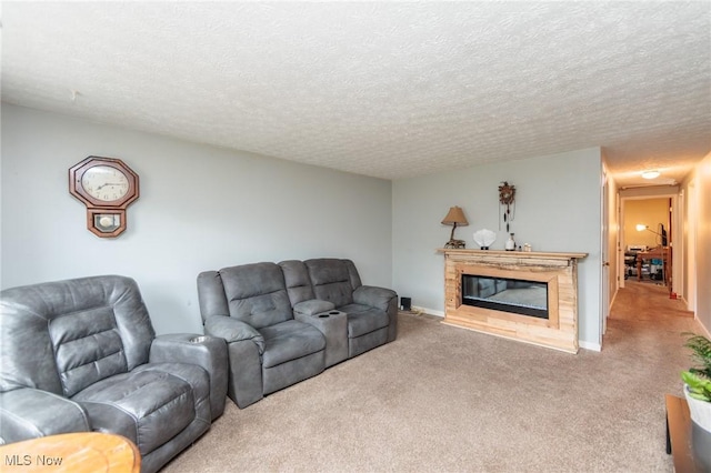 living area with carpet floors, a glass covered fireplace, a textured ceiling, and baseboards