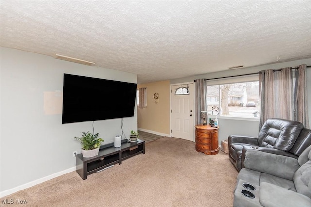 carpeted living room featuring visible vents, a textured ceiling, and baseboards