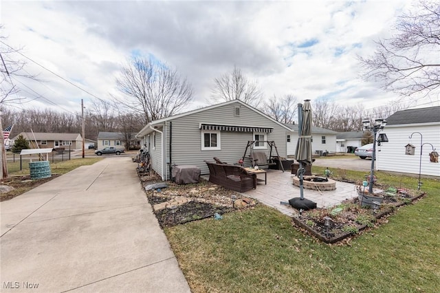 view of front of property featuring concrete driveway, a front yard, a patio area, fence, and a fire pit