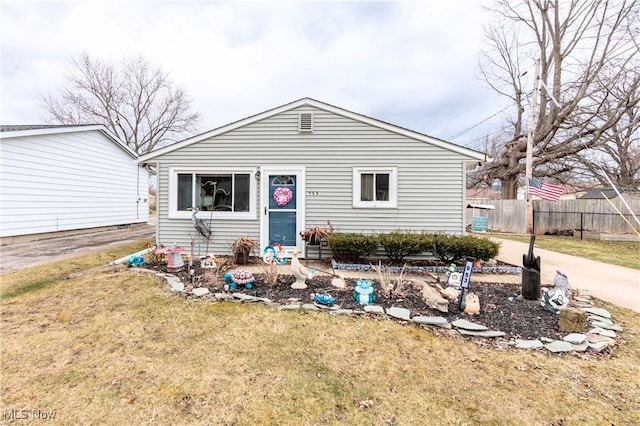 bungalow-style home with fence and a front lawn