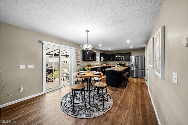 dining area featuring a chandelier, a textured ceiling, baseboards, and wood finished floors