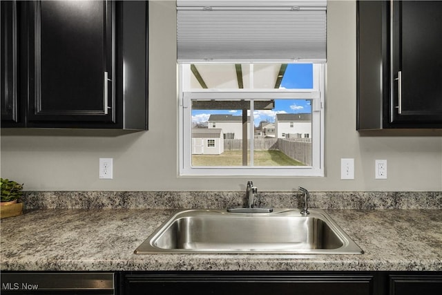 kitchen with light countertops, dark cabinetry, and a sink