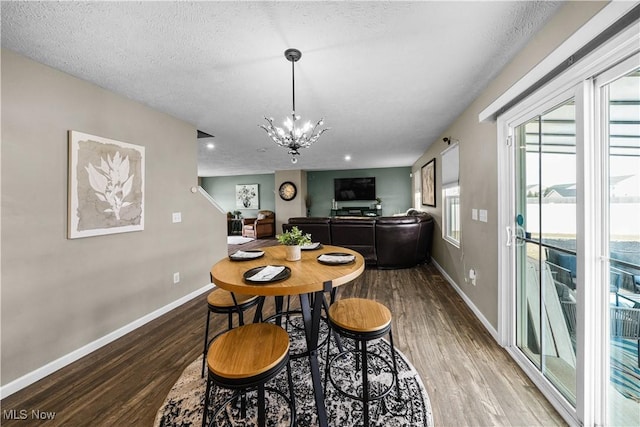 dining space with a textured ceiling, wood finished floors, baseboards, and a chandelier