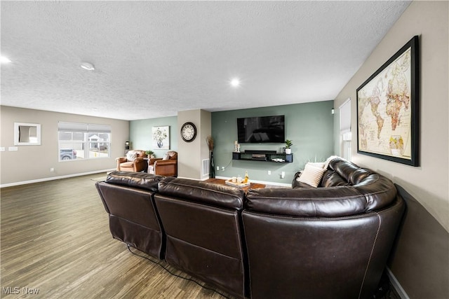 living area with visible vents, baseboards, a textured ceiling, and wood finished floors