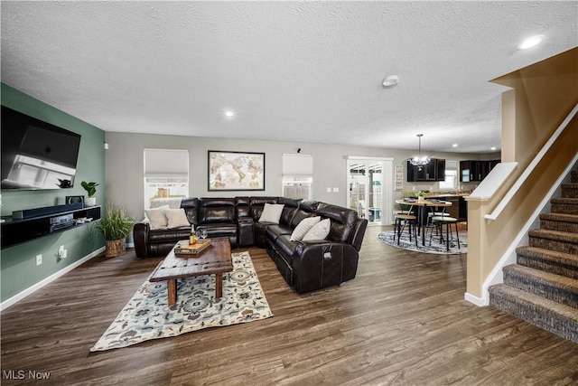 living area with baseboards, a textured ceiling, stairs, and dark wood-type flooring