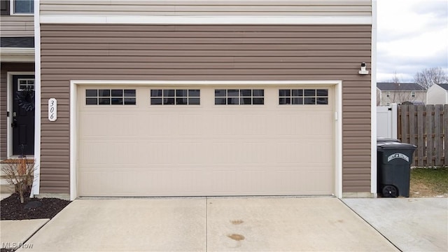 garage featuring concrete driveway and fence