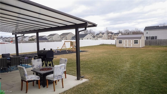 view of yard featuring a playground, a residential view, a storage shed, an outdoor structure, and a patio