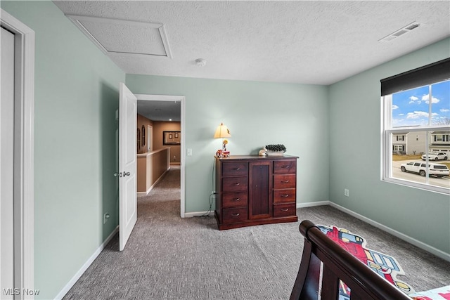 carpeted bedroom featuring visible vents, a textured ceiling, attic access, and baseboards