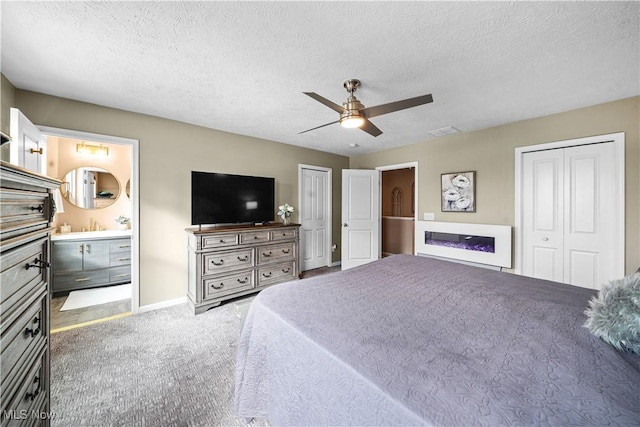 bedroom featuring carpet flooring, a textured ceiling, visible vents, and a glass covered fireplace