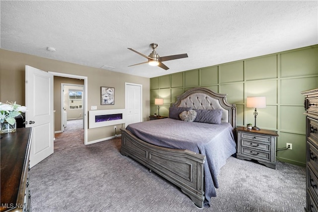 carpeted bedroom featuring ceiling fan, a decorative wall, a closet, and a textured ceiling