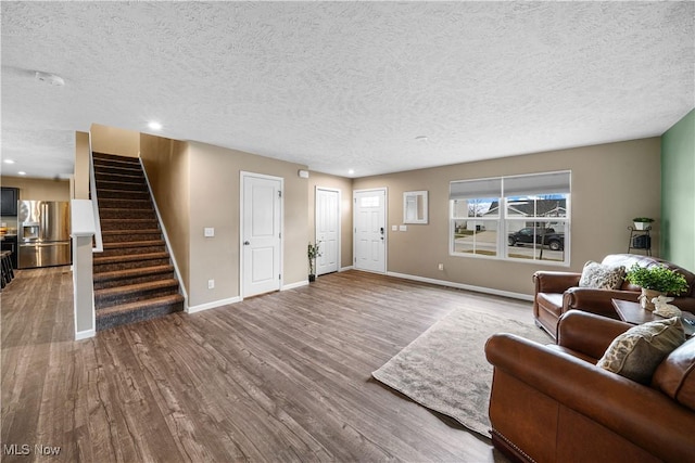 living area featuring wood finished floors, baseboards, recessed lighting, stairs, and a textured ceiling