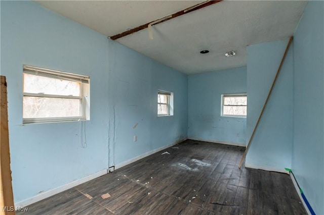 spare room with wood-type flooring and baseboards