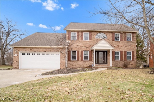 colonial house featuring a garage, a shingled roof, concrete driveway, a front lawn, and brick siding