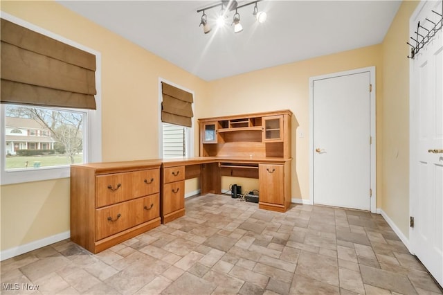 office featuring stone finish flooring, baseboards, and built in desk