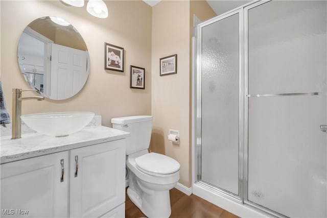 full bath with toilet, a shower stall, vanity, and wood finished floors