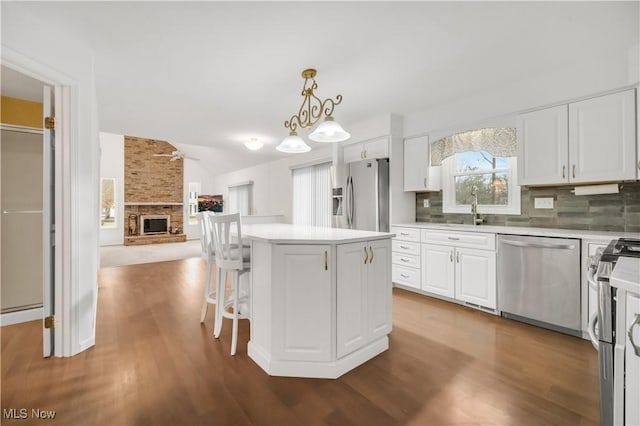 kitchen featuring stainless steel appliances, white cabinetry, open floor plan, light countertops, and backsplash