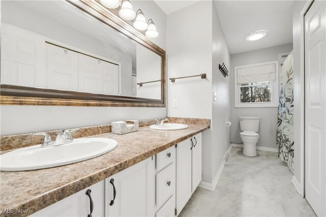 full bath featuring baseboards, a sink, toilet, and double vanity