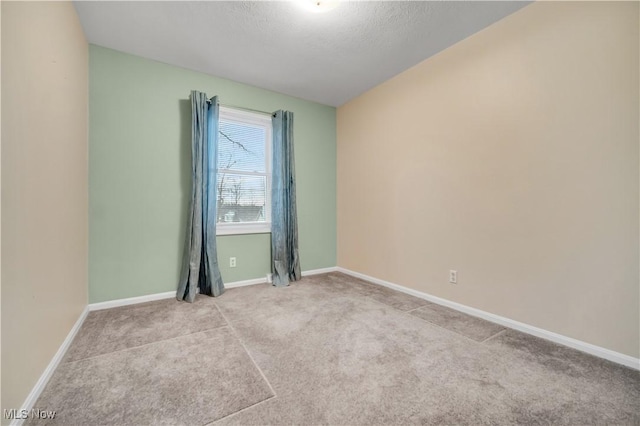 carpeted spare room featuring a textured ceiling and baseboards