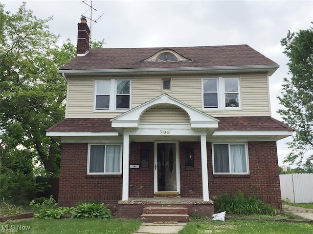 view of front of property featuring roof with shingles, a chimney, fence, and brick siding