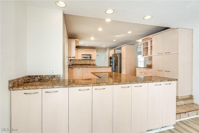 kitchen featuring stone countertops, recessed lighting, stainless steel appliances, a peninsula, and light wood-style floors