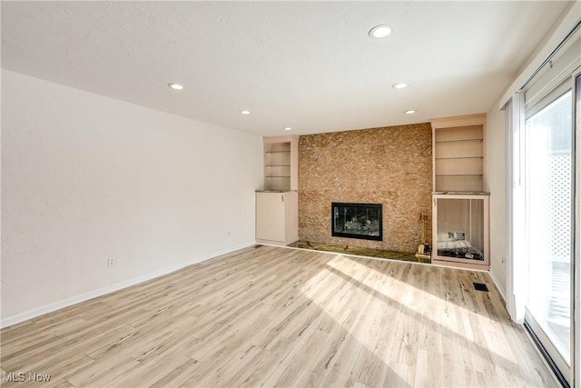 unfurnished living room featuring light wood-type flooring, built in shelves, a fireplace, and baseboards