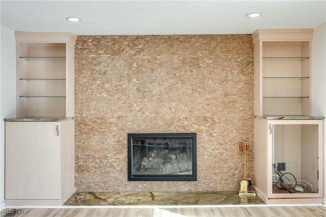 details with a glass covered fireplace, recessed lighting, and wood finished floors