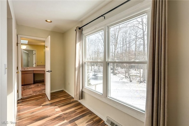 doorway to outside featuring baseboards, a sink, wood finished floors, and a healthy amount of sunlight