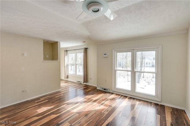 empty room featuring a textured ceiling, wood finished floors, visible vents, and baseboards