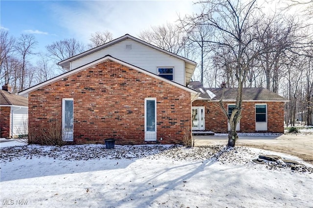 snow covered rear of property with brick siding