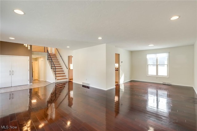 unfurnished room featuring stairs, wood finished floors, visible vents, and recessed lighting