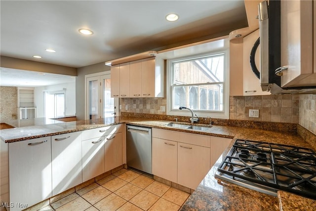 kitchen featuring stainless steel appliances, a peninsula, a sink, and a wealth of natural light