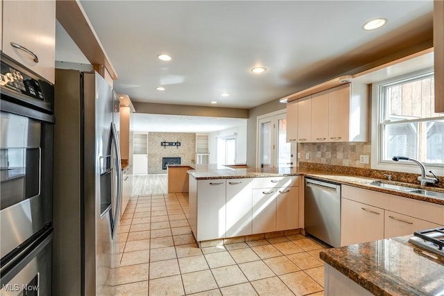 kitchen featuring stainless steel appliances, a wealth of natural light, a sink, and a peninsula