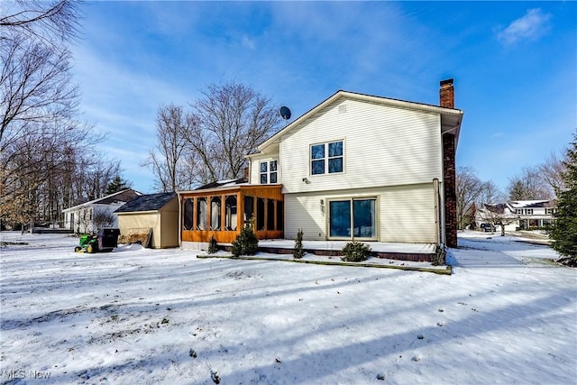 snow covered back of property featuring a chimney