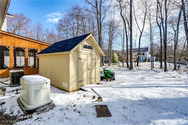 snow covered structure featuring an outbuilding, a shed, and central AC unit