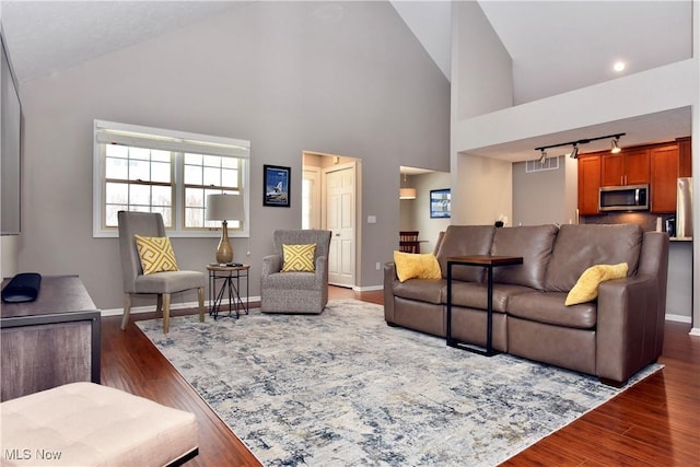 living area with dark wood-style floors, rail lighting, and baseboards